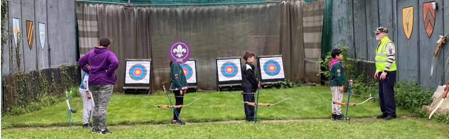 Photo of Cubs with arrows and bows in hand at the archery range.